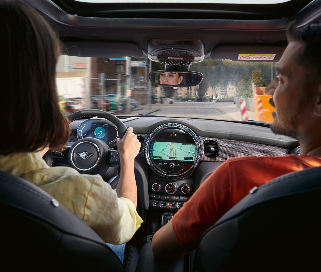 Look over the right shoulder of a woman driving her MINI Hardtop 2 Door.